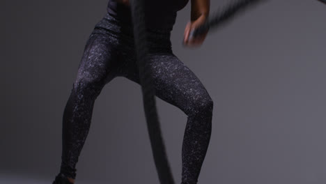 Close-Up-Studio-Shot-Of-Mature-Woman-Wearing-Gym-Fitness-Clothing-Doing-Cardio-Exercise-With-Battle-Ropes-3